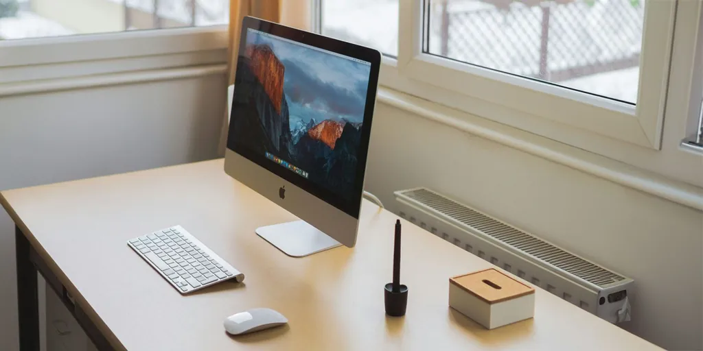 ジョニー・アイブのAIハードウェアデバイスに関するこの説はますます真実味を帯びてきている | iMac、キーボード、マウス、ペンスタンド、箱が置かれた机
